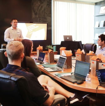 man standing in front of people sitting beside table with laptop computers